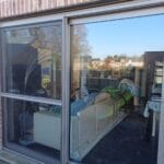 Small, enclosed outdoor space with white perimeter walls, a single window, a round gray planter, and lush, long green grass, in Dallas