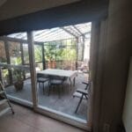 Indoor view looking out to a small, private courtyard with unkempt grass, a modern round planter, and a glimpse of the sky through a window